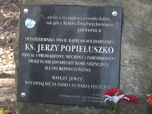 Setki zniczy i kwiaty przey krzyżu w miejscu porwania ks. Jerzego Popiełuszki